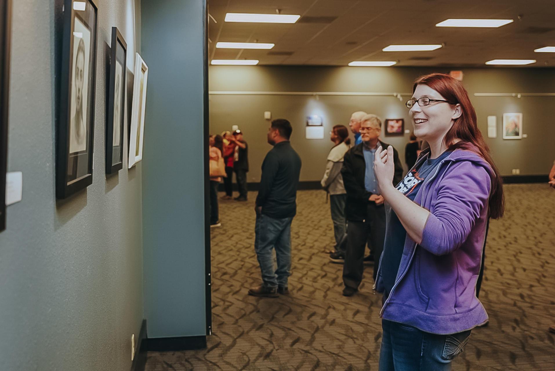 TSC English Instructor Amanda Utzman views a variety of portraits on display as the exhibit.